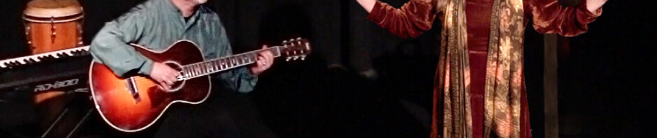 Diane in brown velvet arms spread wide. Theatre setting - Tom beside her accompanies the story on Guitar